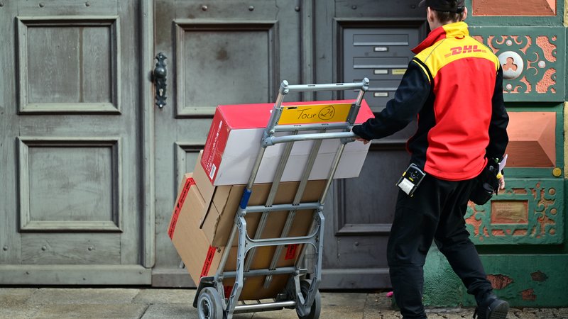 Ein DHL Mitarbeiter liefert Sendungen aus. | Bild: picture alliance/dpa | Martin Schutt Ein DHL Mitarbeiter liefert Sendungen aus.