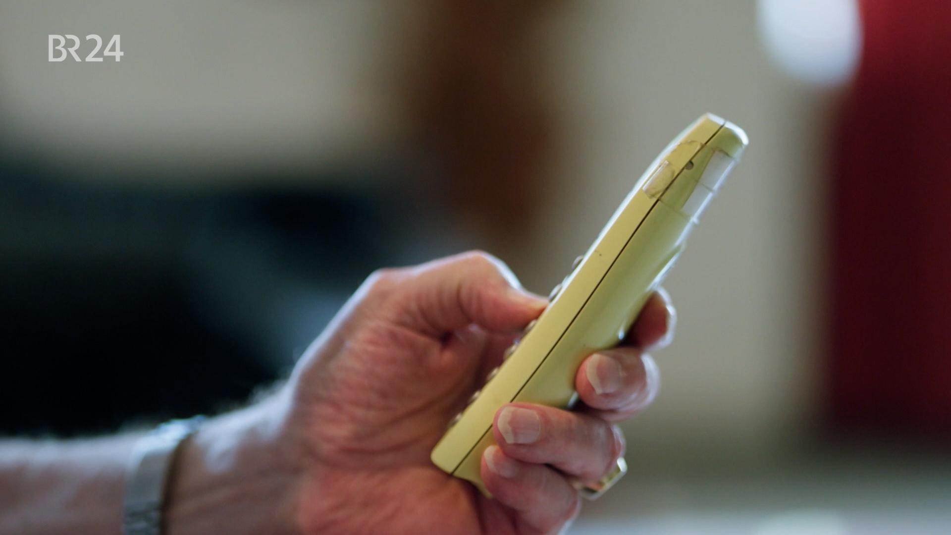 Hand des Senioren hält Telefon