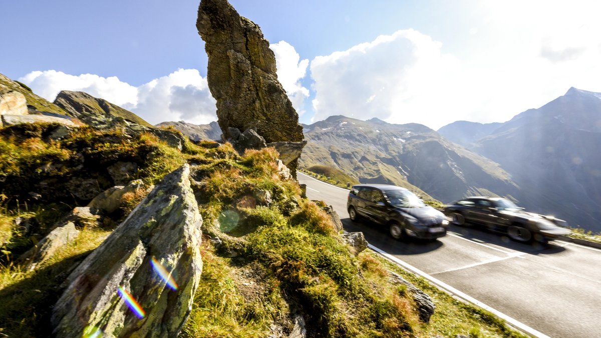 Autos in den Alpen: zwei schnelle Fahrzeuge beim Großglockner in Österreich. Straßenverkehr macht einen der größten Anteile beim CO2-Ausstoß aus.
