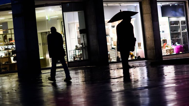 Passanten laufen in einer dunklen Straße an Geschäften vorbei (Symbolbild) | Bild:pa/dpa/Julian Stratenschulte