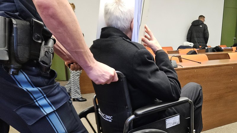 Der Angeklagte wird am 21.1.25 in einem Rollstuhl in den Saal des Landgerichts München I geschoben. | Bild: dpa-Bildfunk/Cordula Wildauer Der Angeklagte wird am 21.1.25 in einem Rollstuhl in den Saal des Landgerichts München I geschoben.