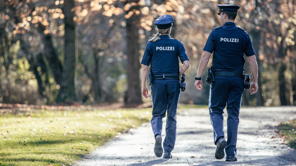 Ein Polizist und eine Polizistin gehen in einem Park auf Streife (Symbolbild)