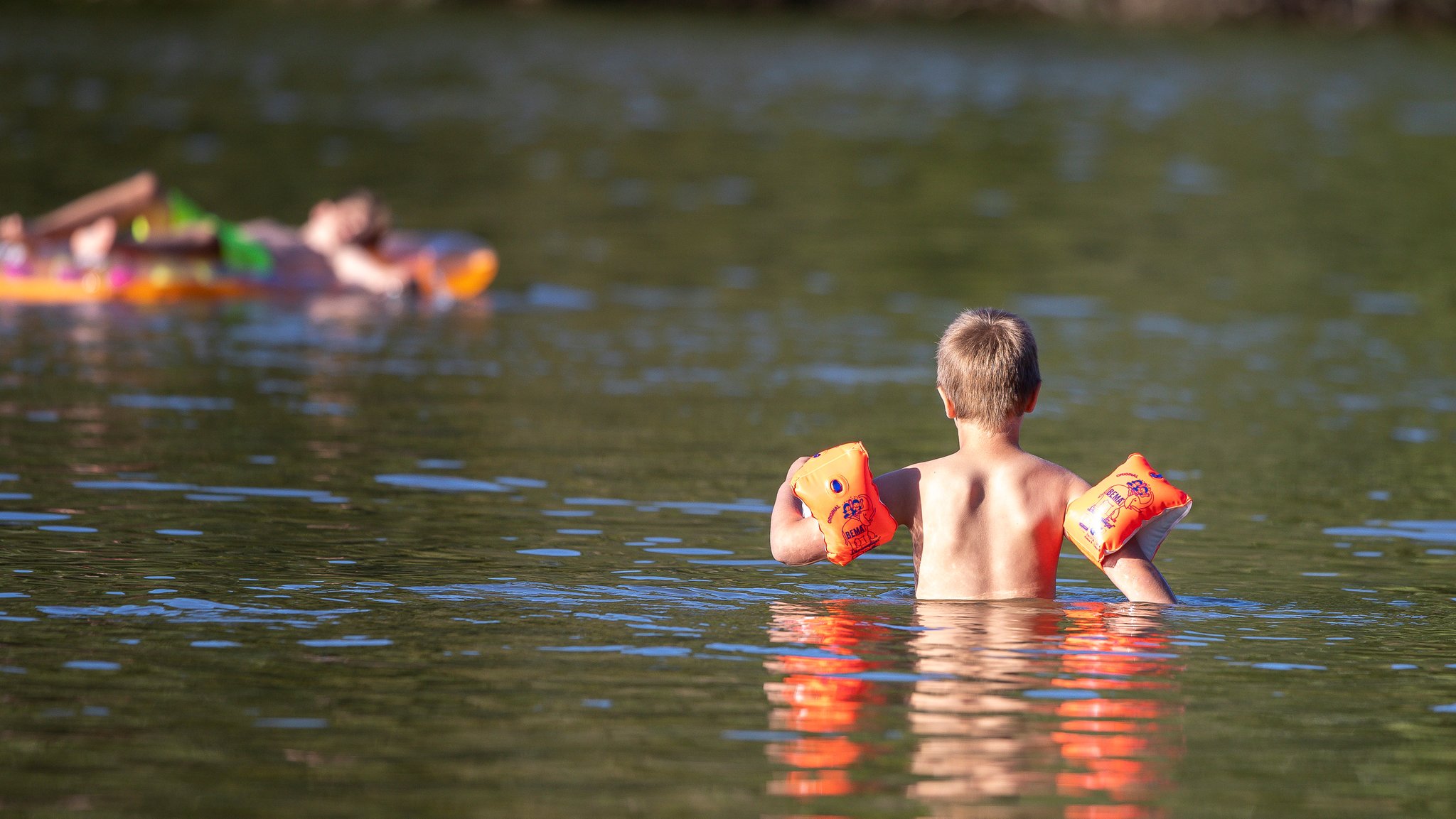 Kind mit Schwimmflügeln in einem Bdesee