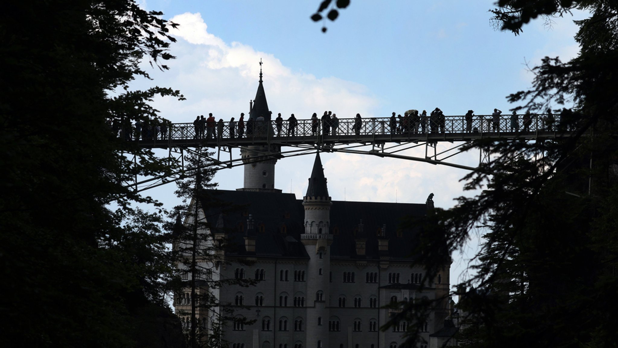 Touristen stehen auf der Marienbrücke vor dem Schloss Neuschwanstein.