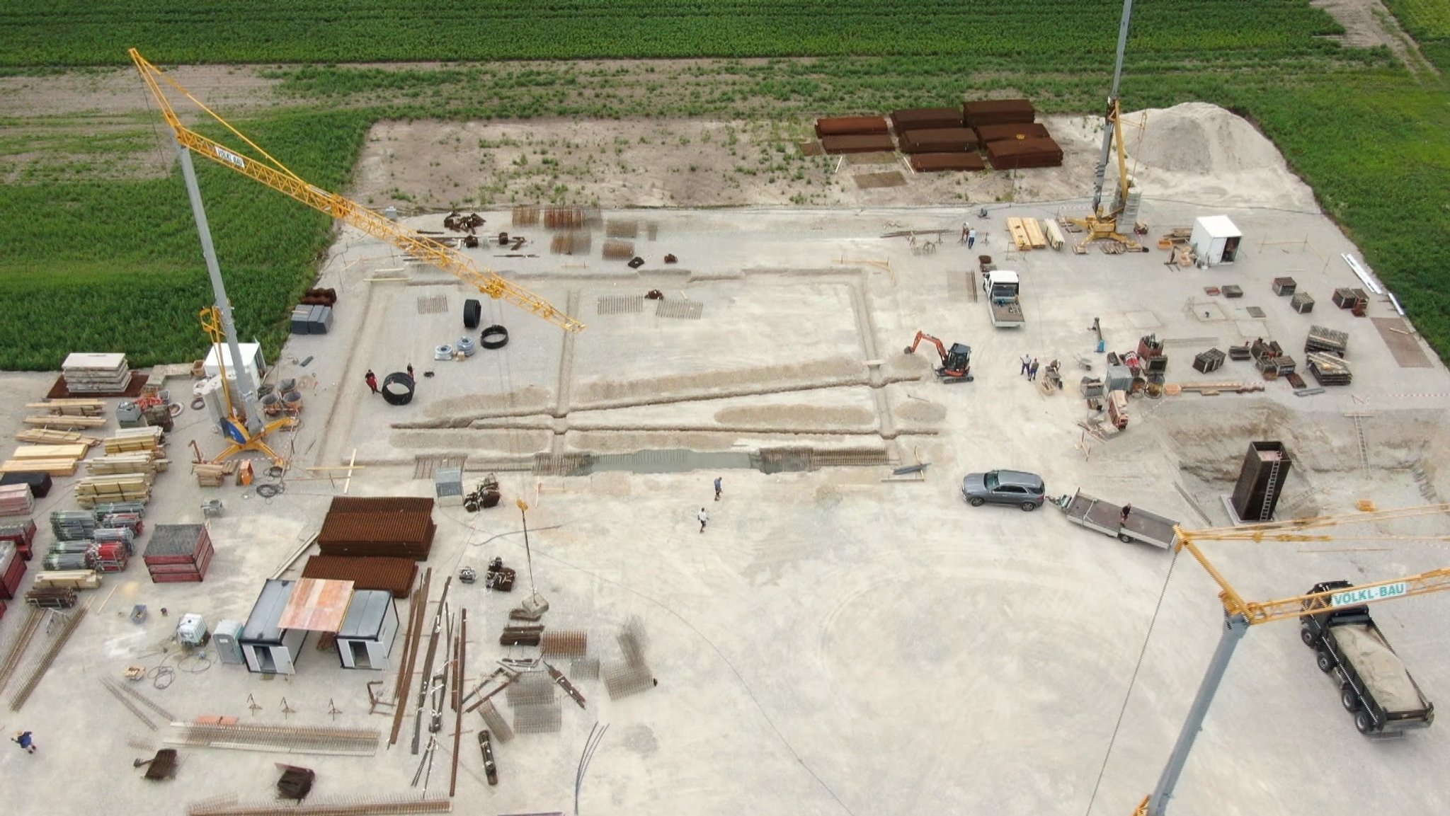 Drohnenansicht von oben auf die Baustelle mit drei Kränen