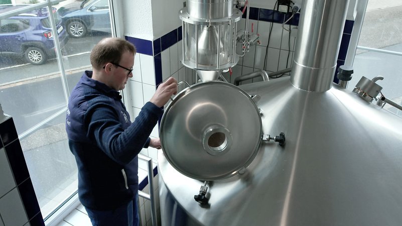 Ein Mann mit Brille schaut in einen Braukessel. | Bild: BR Ein Mann mit Brille schaut in einen Braukessel.