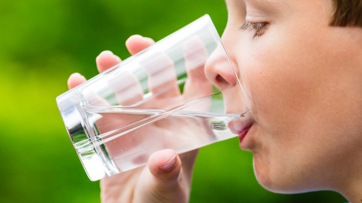 Ein Junge im Profil, der aus einem Glas Wasser trinkt