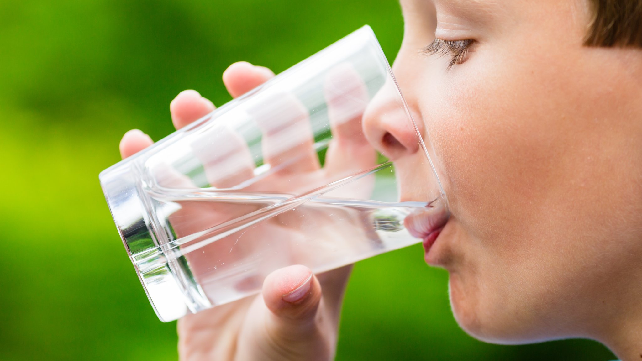 Ein Junge im Profil, der aus einem Glas Wasser trinkt