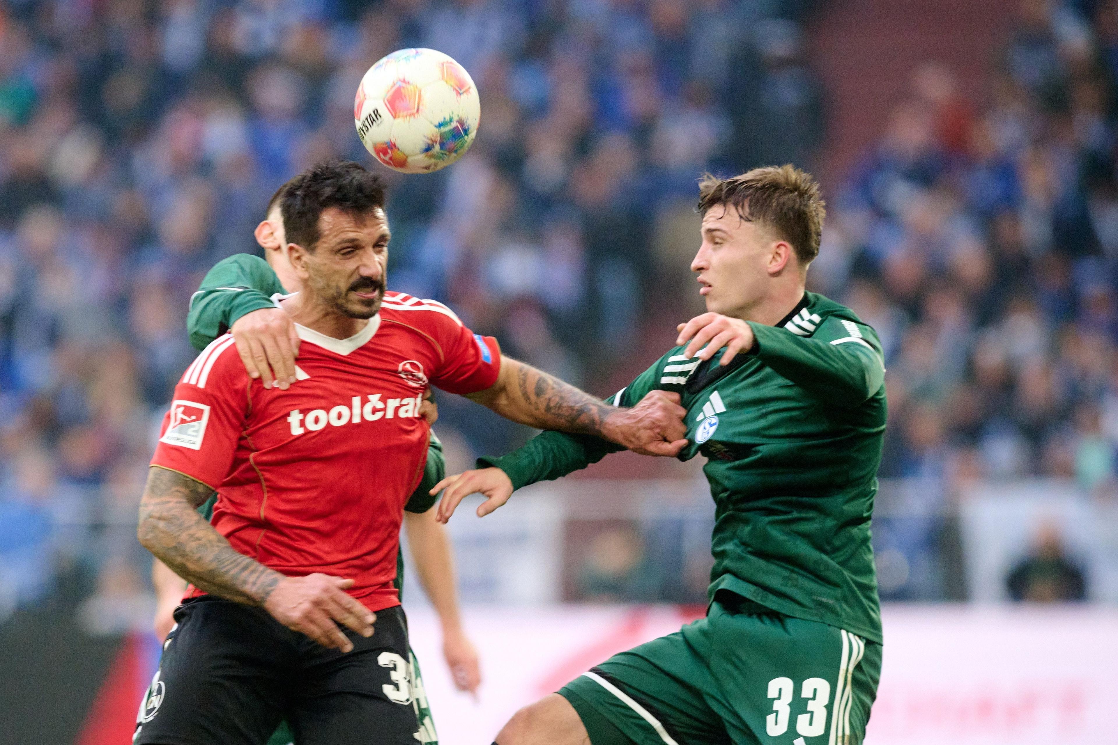 14.12.2025, Nordrhein-Westfalen, Gelsenkirchen: Fußball: 2. Bundesliga, FC Schalke 04 - 1. FC Nürnberg, 16. Spieltag, Veltins Arena. Adriano Grimaldi (1. FC Nürnberg, l.) und Vitalie Becker (FC Schalke 04) in Aktion. Foto: Bernd Thissen/dpa - WICHTIGER HINWEIS: Gemäß den Vorgaben der DFL Deutsche Fußball Liga bzw. des DFB Deutscher Fußball-Bund ist es untersagt, in dem Stadion und/oder vom Spiel angefertigte Fotoaufnahmen in Form von Sequenzbildern und/oder videoähnlichen Fotostrecken zu verwerten bzw. verwerten zu lassen. +++ dpa-Bildfunk +++