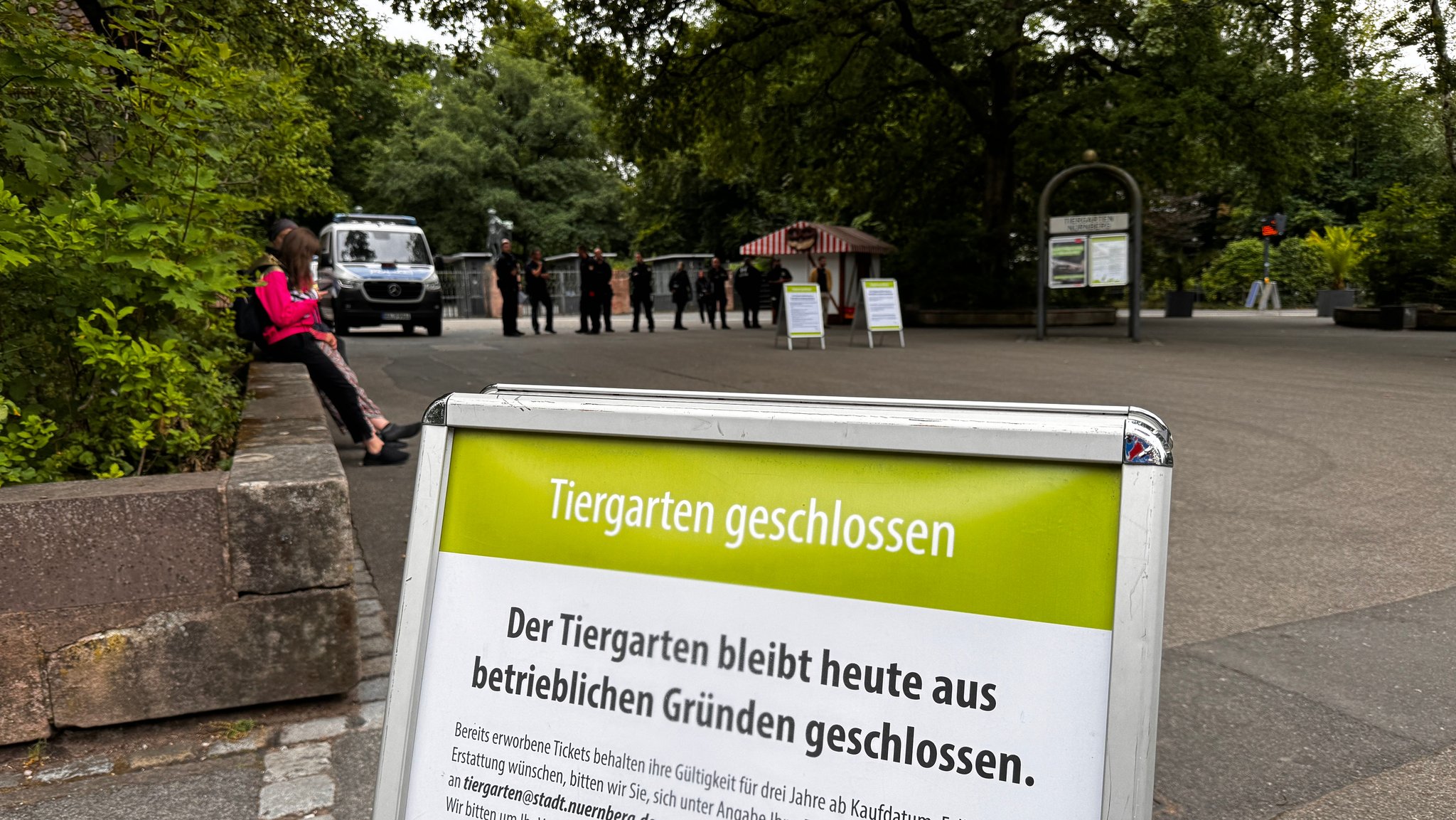 Ein Schild mit der Aufschrift: Tiergarten geschlossen. Im Hintergrund stehen Polizisten vor dem Eingang. 