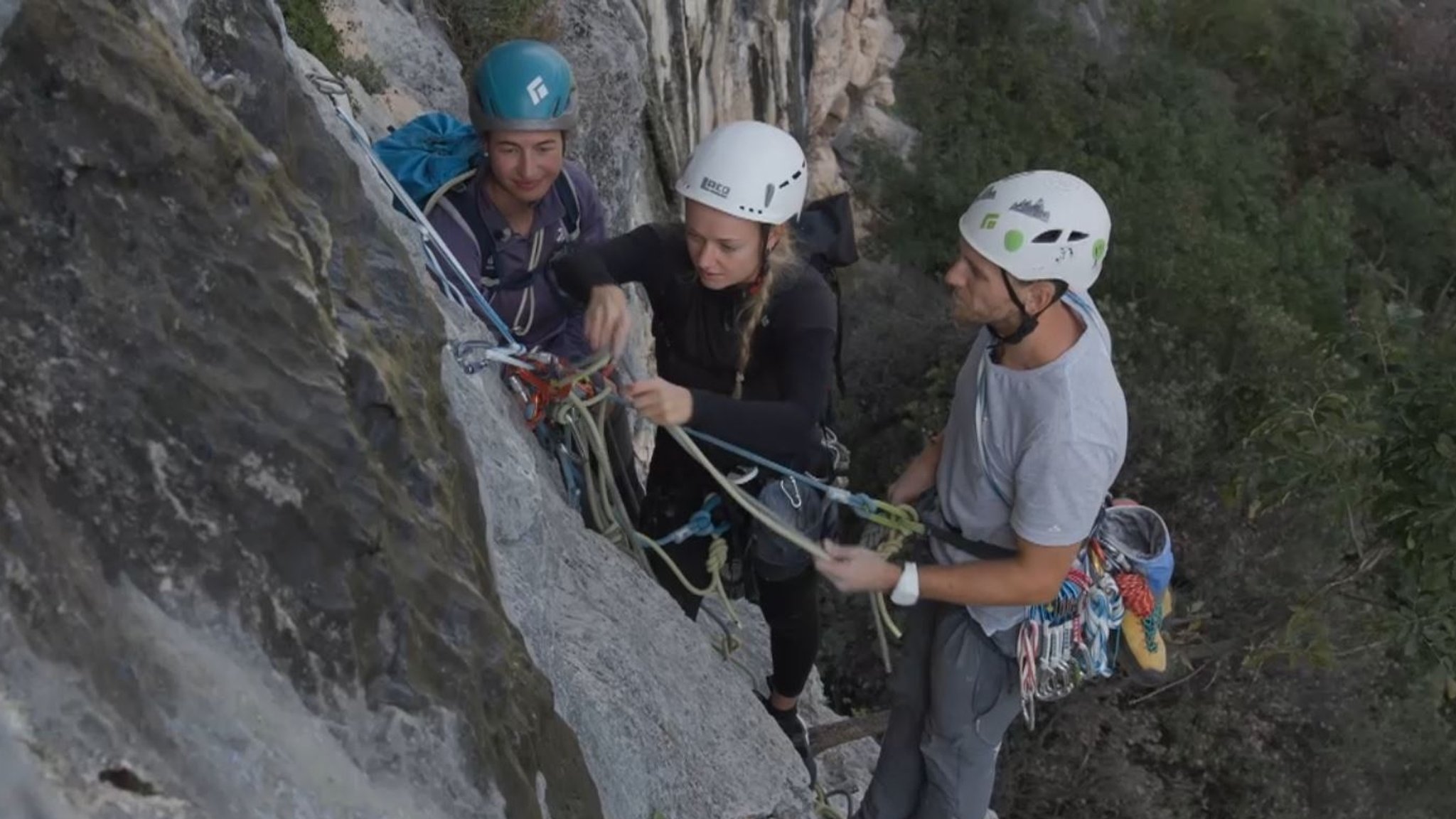 Bergführerin Monika Hümmer baut am Felsen mit zwei Teilnehmenden einen Standplatz im VDBS Evaluation Camp in Arco.