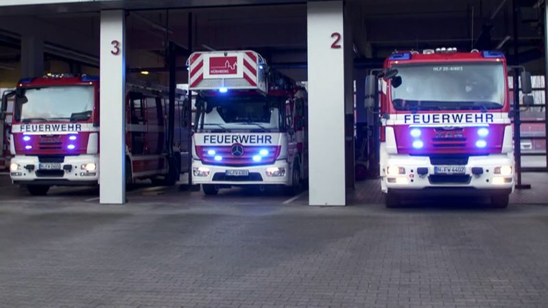 Drei Feuerwehrautos parken in einem Feuerwehrhaus.