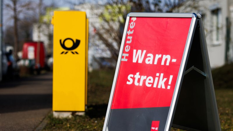 Ein Aufsteller mit der Aufschrift "Heute Warnstreik!" steht neben einem Briefkasten der Deutschen Post. | Bild: dpa-Bildfunk/Philipp von Ditfurth Ein Aufsteller mit der Aufschrift "Heute Warnstreik!" steht neben einem Briefkasten der Deutschen Post.