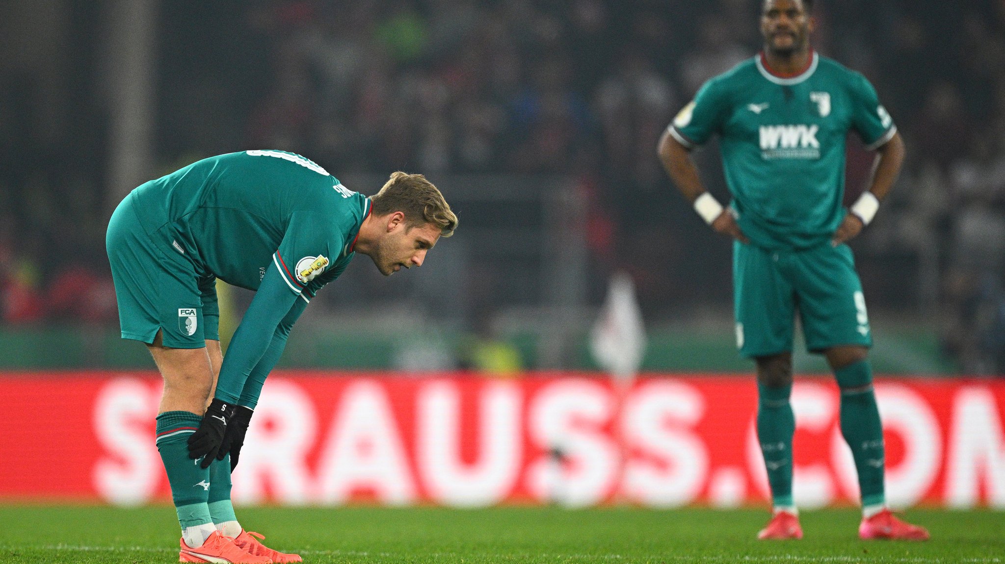 04.02.2025, Baden-Württemberg, Stuttgart: Fußball, DFB-Pokal, VfB Stuttgart - FC Augsburg, Viertelfinale, MHPArena, Augsburgs Arne Maier (l) und Augsburgs Samuel Essende stehen enttäuscht auf dem Platz. 