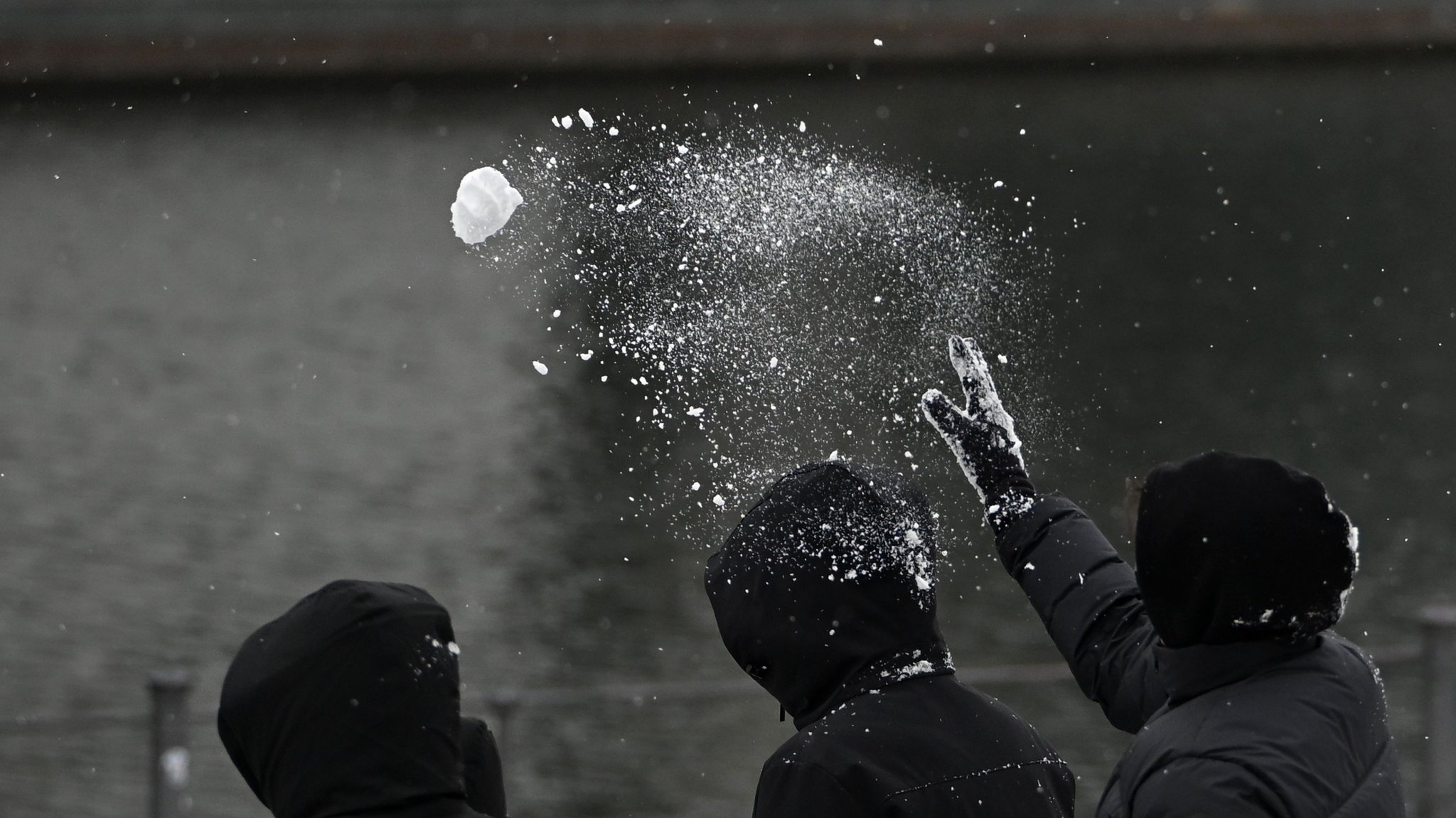 Ein Mann wirft einen Schneeball an einem Flussufer. Er trägt schwarze Kleidung und eine Kapuze. | Bild: dpa-Bildfunk/Markus Lenhardt Ein Mann wirft einen Schneeball an einem Flussufer. Er trägt schwarze Kleidung und eine Kapuze.
