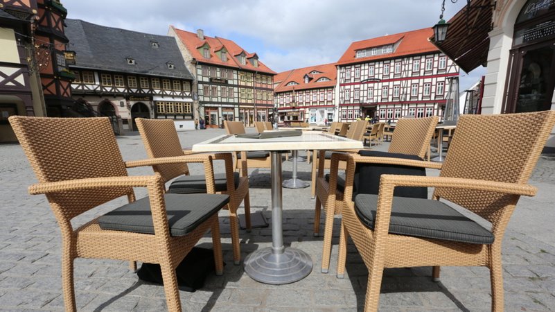 Auf dem Marktplatz in Wernigerode (Sachsen-Anhalt) stehen leere Tische und Stühle vor einem Café.