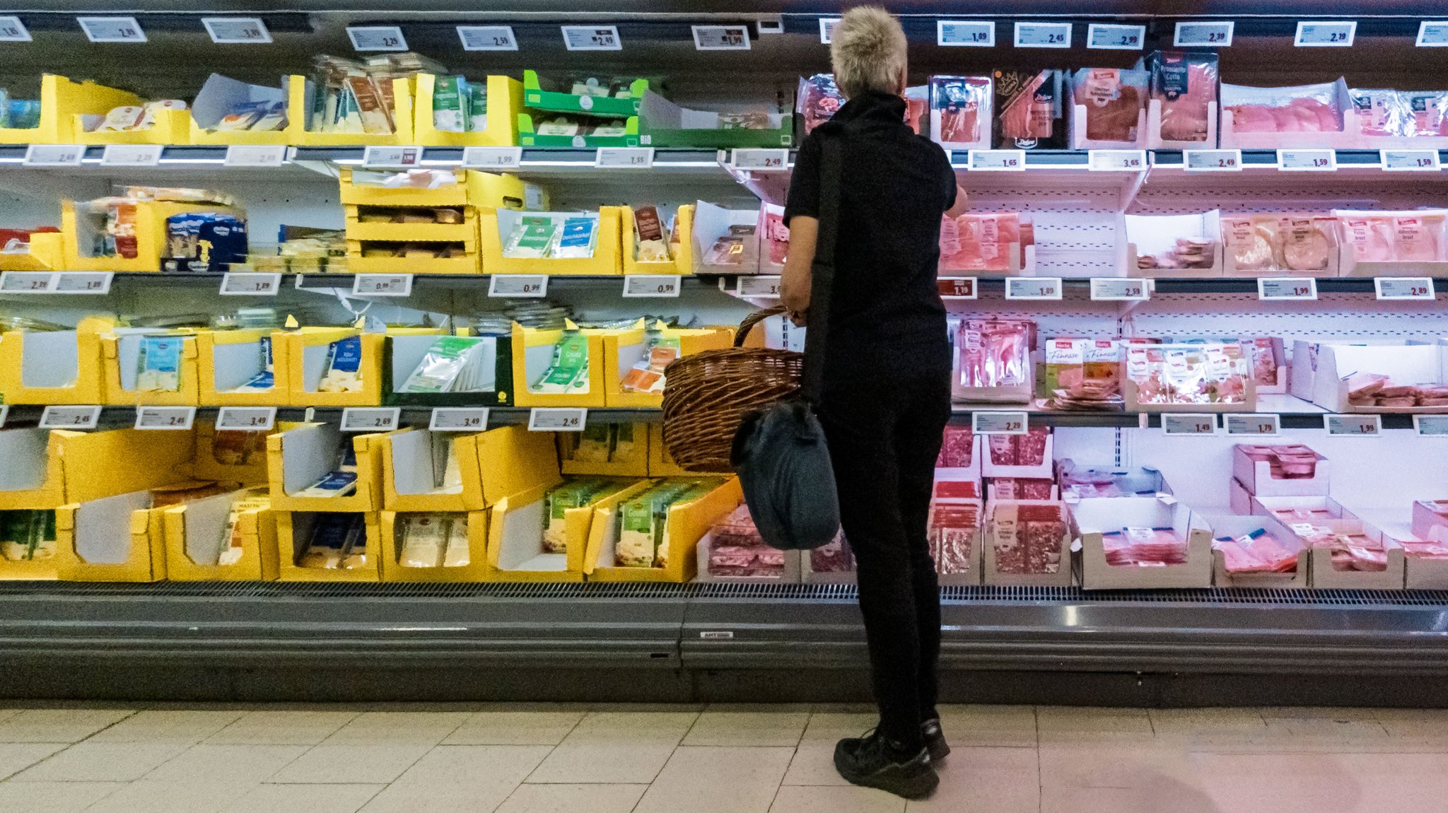 Eine Kundin betrachtet Angebote im Kühlregal eines Supermarkts (Archiv- und Symbolbild)