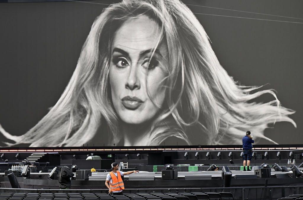 Ein Veranstaltungstechniker vor einer großen Leinwand mit einem Porträt der Sängerin Adele in der Adele World in München.