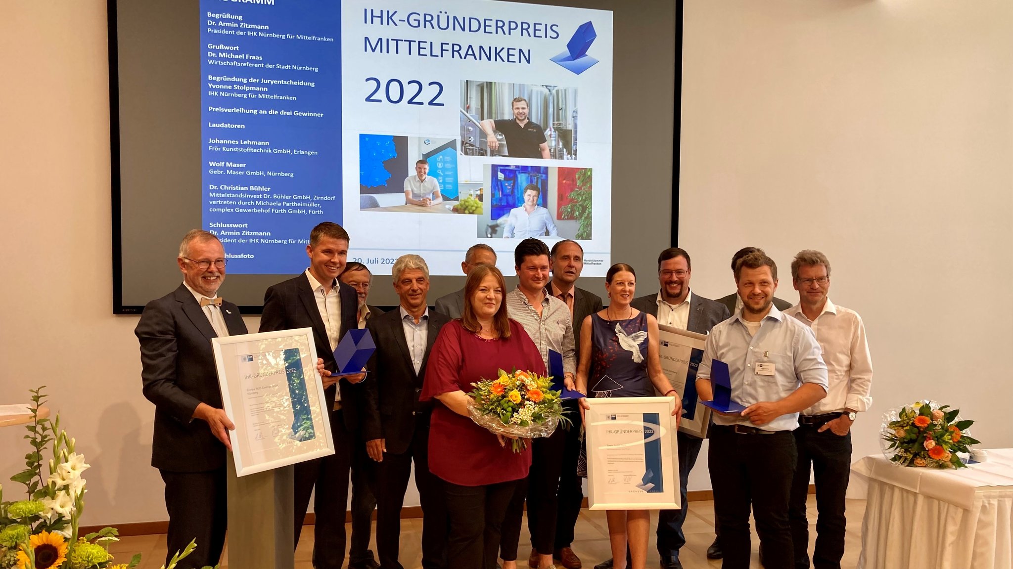 Menschen vor einer Leinwand mit der Aufschrift "IHK-Gründerpreis Mittelfranken".