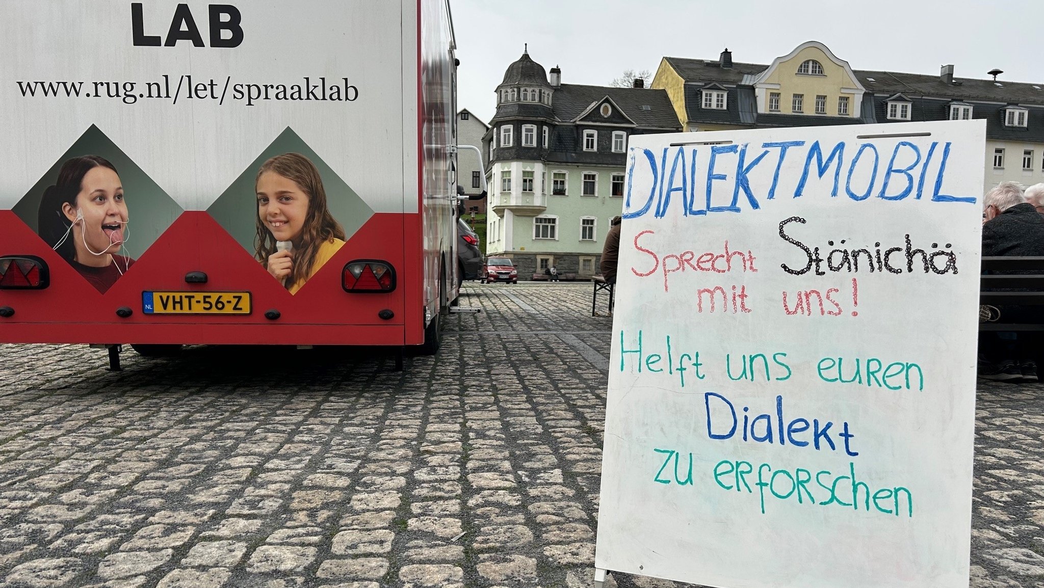 Ein Schild vor einem mobilen Sprachlabor aus den Niederlanden fordert die Bürger im südthüringischen Steinach dazu auf, mit Wissenschaftlern Dialekt zu reden.