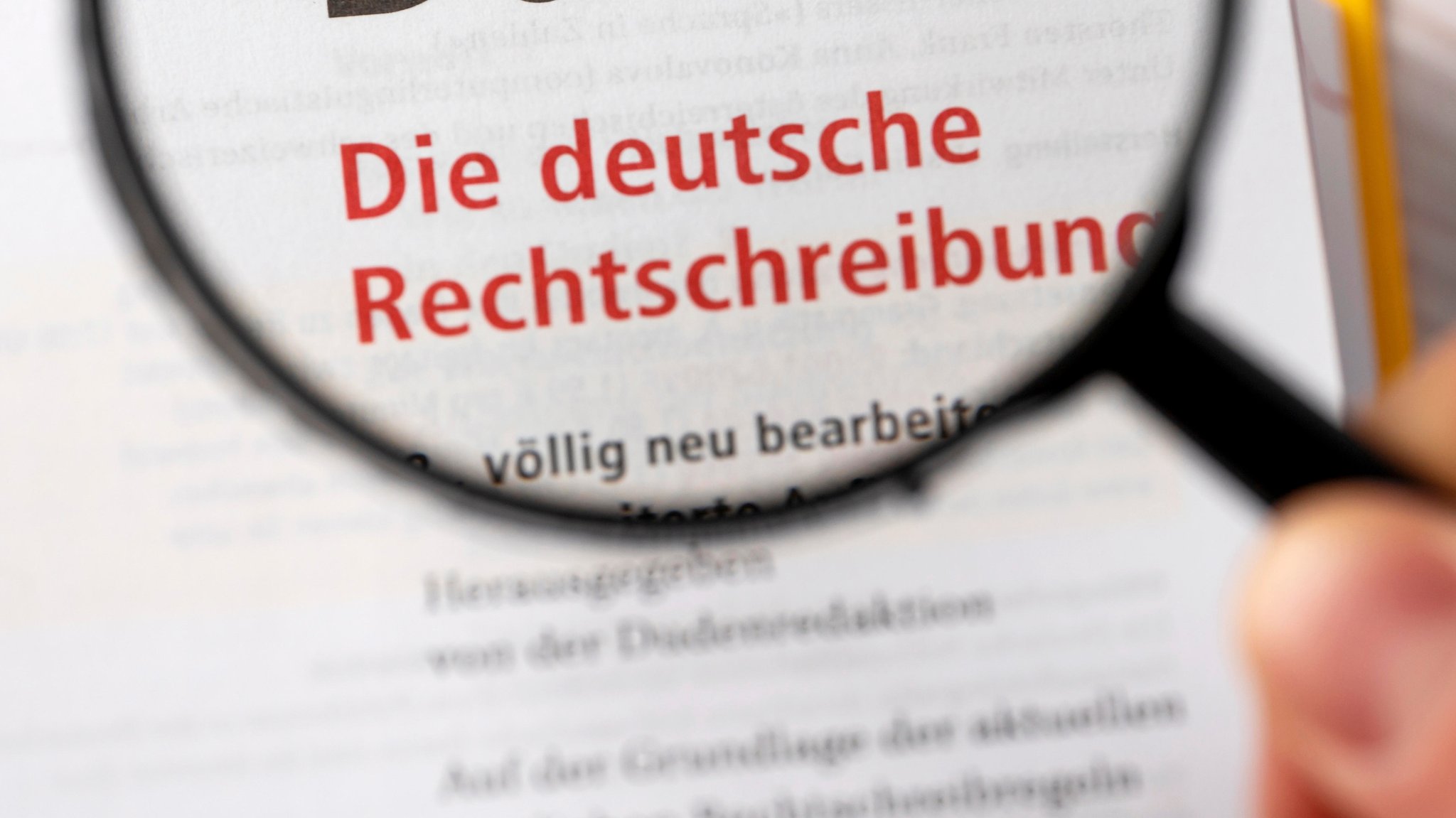 Lupe über einem Duden mit der Aufschrift "Die deutsche Rechtschreibung" (Symbolbild)