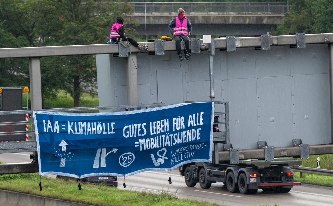 Klimaaktivisten demonstrieren mit einem Plakat auf der A9 nahe der Allianz Arena gegen die IAA.