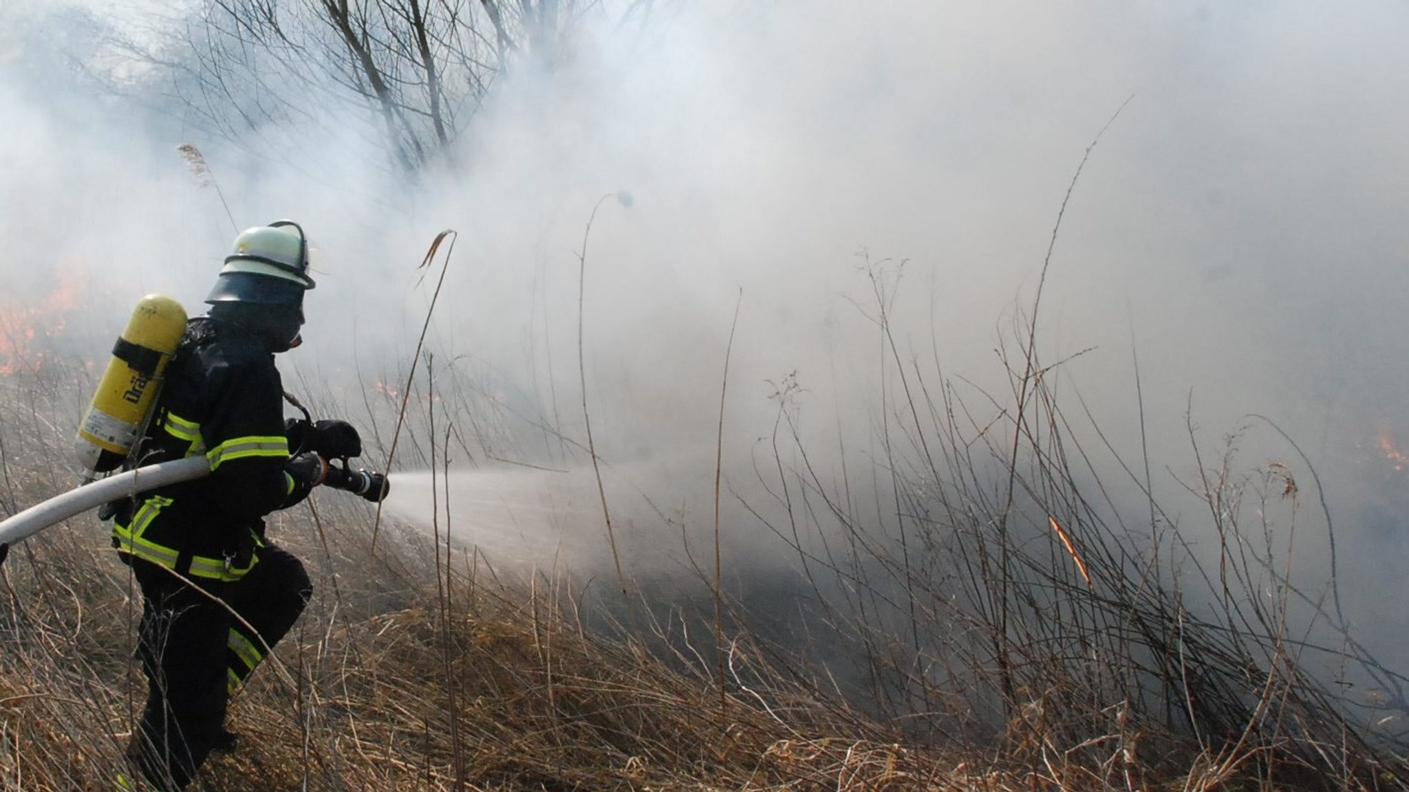 Feuerwehrmann löscht Flächenbrand (Symbolbild)