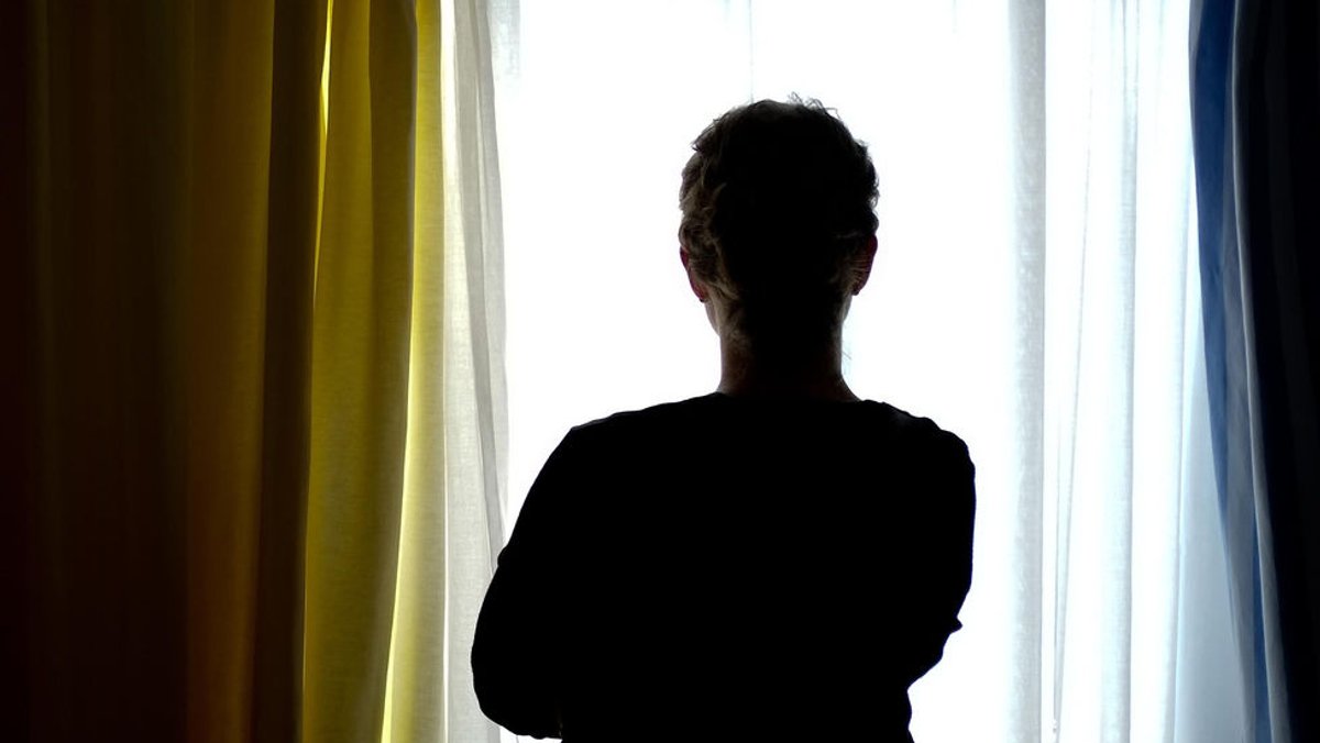 Eine junge Frau steht in einem Zimmer eines Frauenhauses.