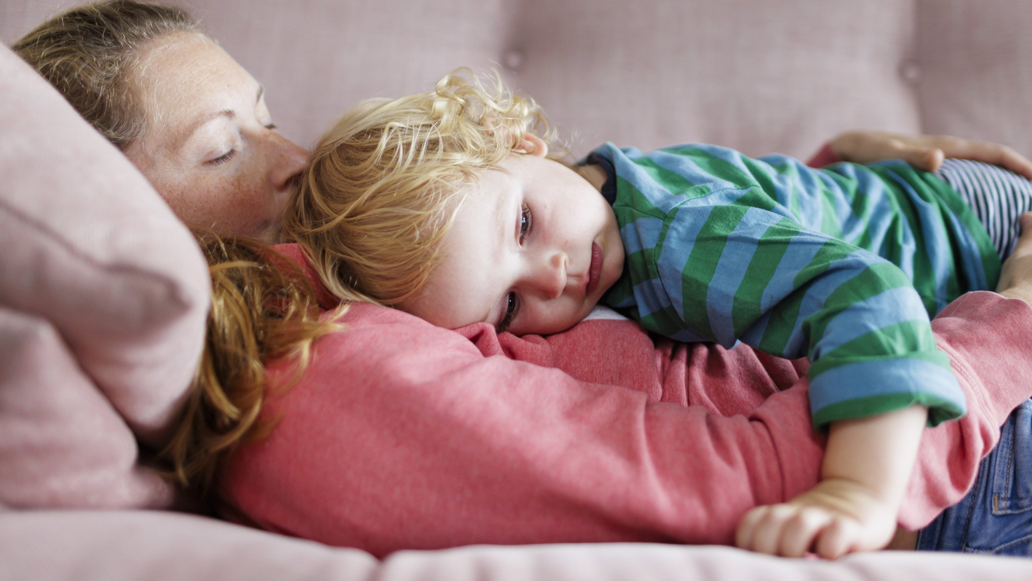 Ein Kind liegt kuschelnd auf dem Bauch seiner Mutter