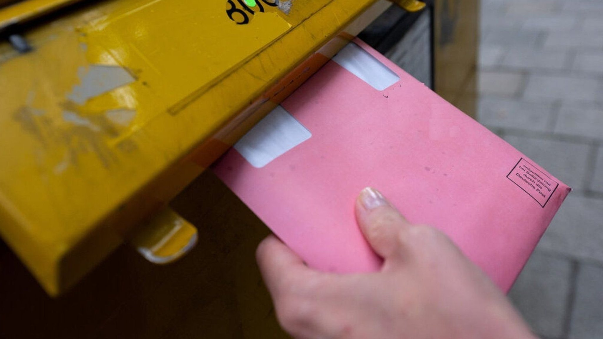 Briefwähler wirft seine Wahlscheine im roten Rücksende-Kuvert in den Postkasten.