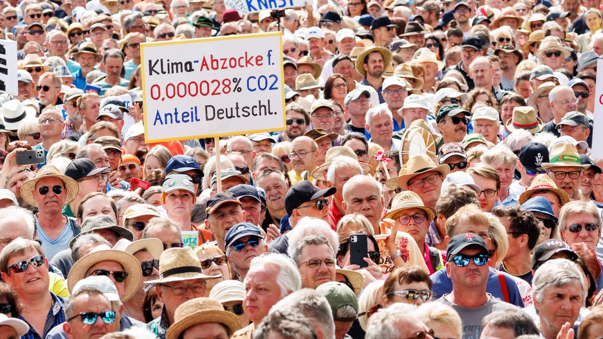 Teilnehmer halten bei einer Demonstration gegen die Klima-Politik der Ampelregierung unter dem Motto "Stoppt die Heizungsideologie" Schilder in die Höhe, unter anderem mit der Aufschrift "Klima-Abzocke f. 0,000028% CO2 Anteil Deutschl.".