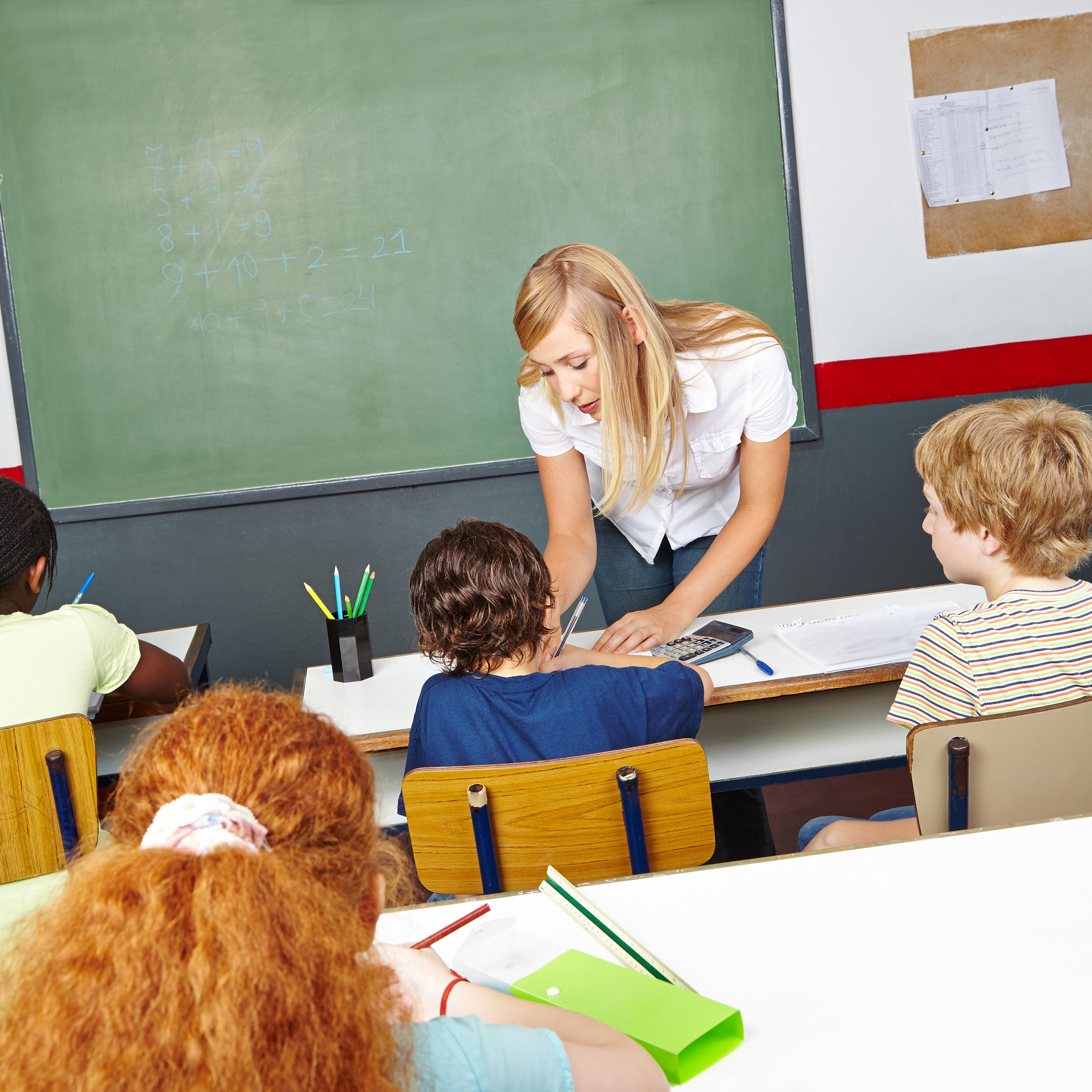 Junge Frau hilft Schülern in der Grundschule