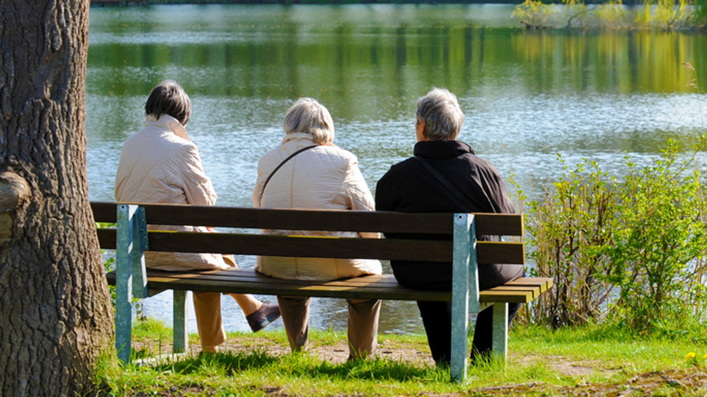 Symbolbild: Senioren sitzen auf einer Bank an einem See. 