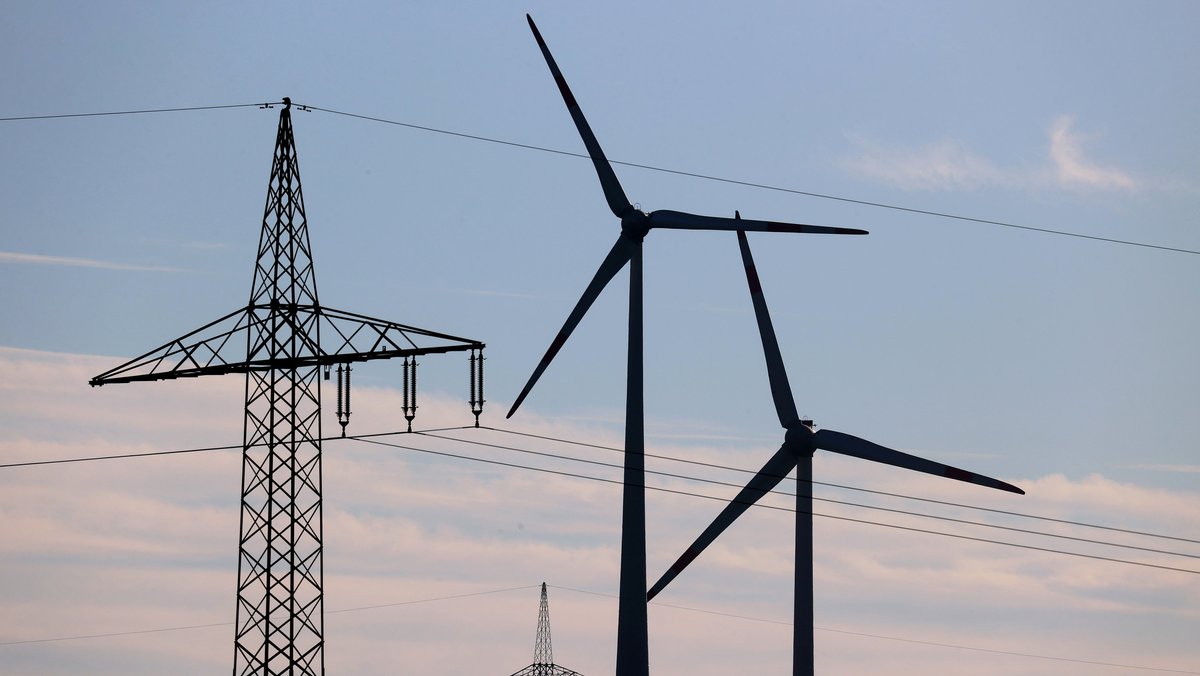 Bayern, Biebelried: Windräder stehen vor den Masten einer Stromtrasse