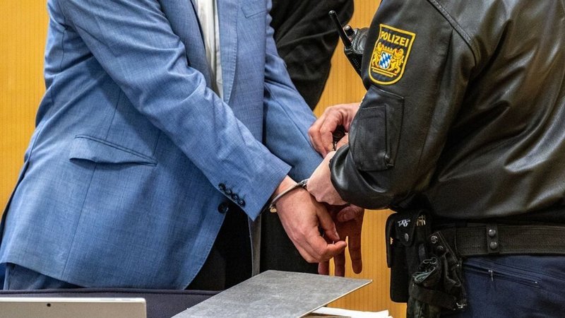 Polizist im Gerichtsaal nimmt dem Angeklagten die Handschellen ab