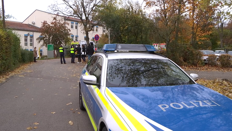 Ein Polizeiauto, Rettungswagen und mehrere Menschen stehen vor der Regensburger Psychiatrie, in der sich die Blutttat ereignet hat.