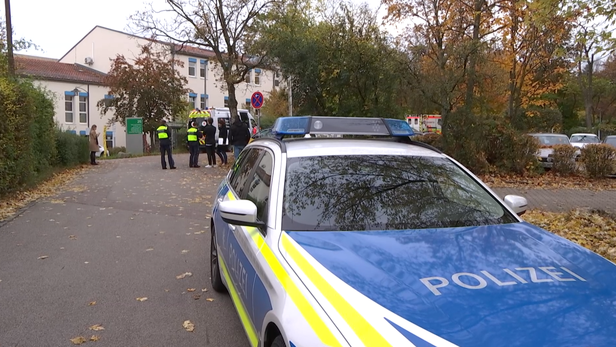 Ein Polizeiauto, Rettungswagen und mehrere Menschen stehen vor der Regensburger Psychiatrie, in der sich die Blutttat ereignet hat.