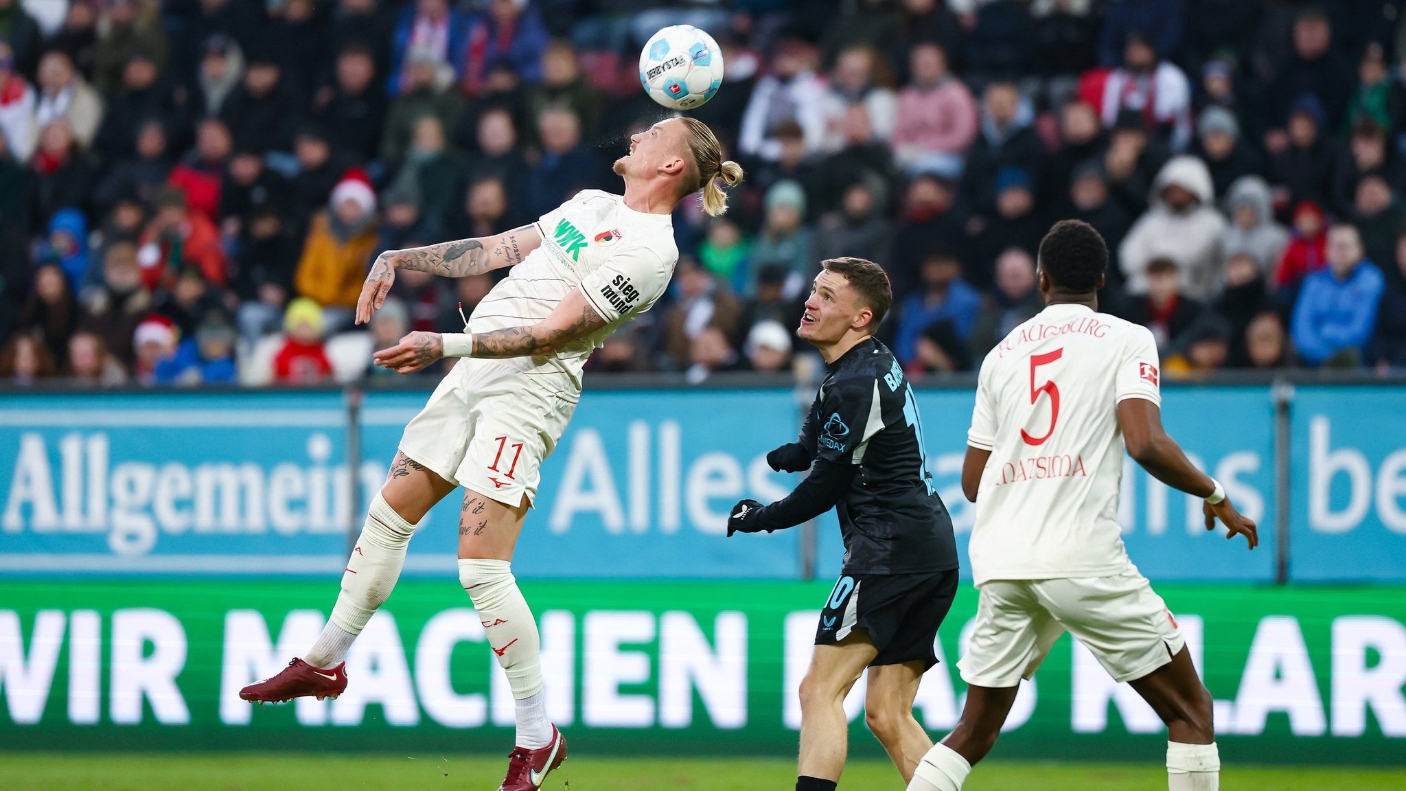 14.12.2024, Bayern, Augsburg: Fußball: Bundesliga, FC Augsburg - Bayer Leverkusen, 14. Spieltag, WWK-Arena. Marius Wolf vom FC Augsburg (l) und Florian Wirtz von Bayer Leverkusen in Aktion. Foto: Daniel Löb/dpa - WICHTIGER HINWEIS: Gemäß den Vorgaben der DFL Deutsche Fußball Liga bzw. des DFB Deutscher Fußball-Bund ist es untersagt, in dem Stadion und/oder vom Spiel angefertigte Fotoaufnahmen in Form von Sequenzbildern und/oder videoähnlichen Fotostrecken zu verwerten bzw. verwerten zu lassen. +++ dpa-Bildfunk +++