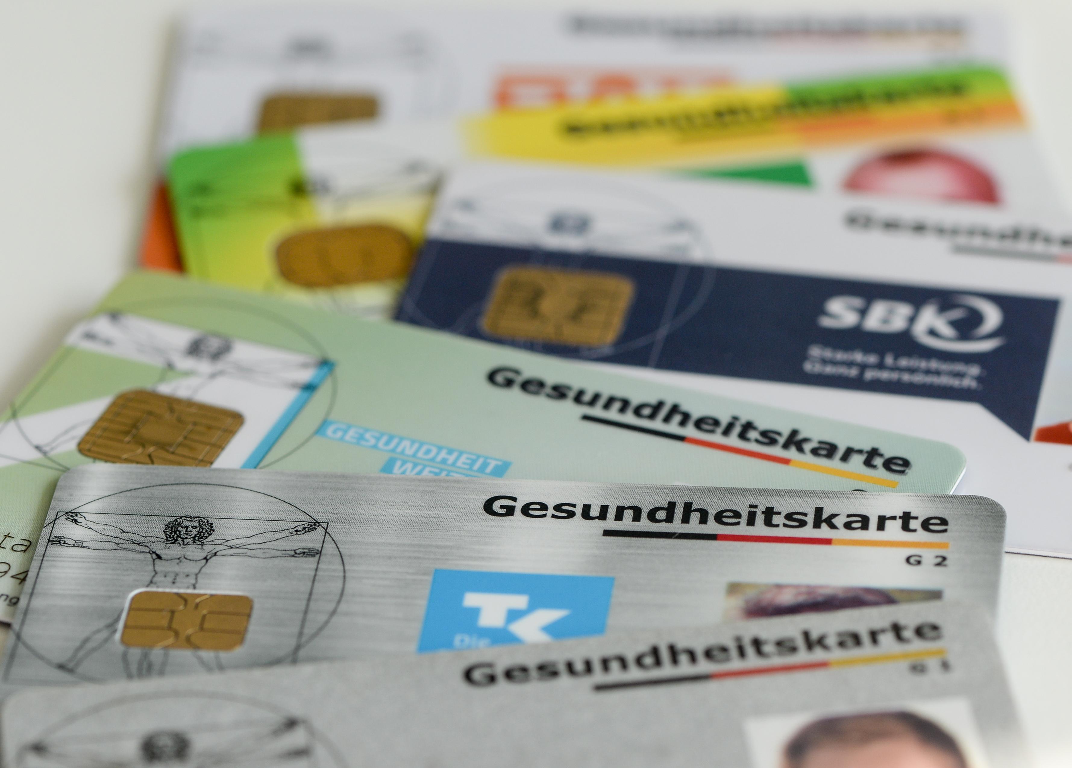 Gesundheitskarten verschiedener Krankenkassen liegen auf einem Tisch.