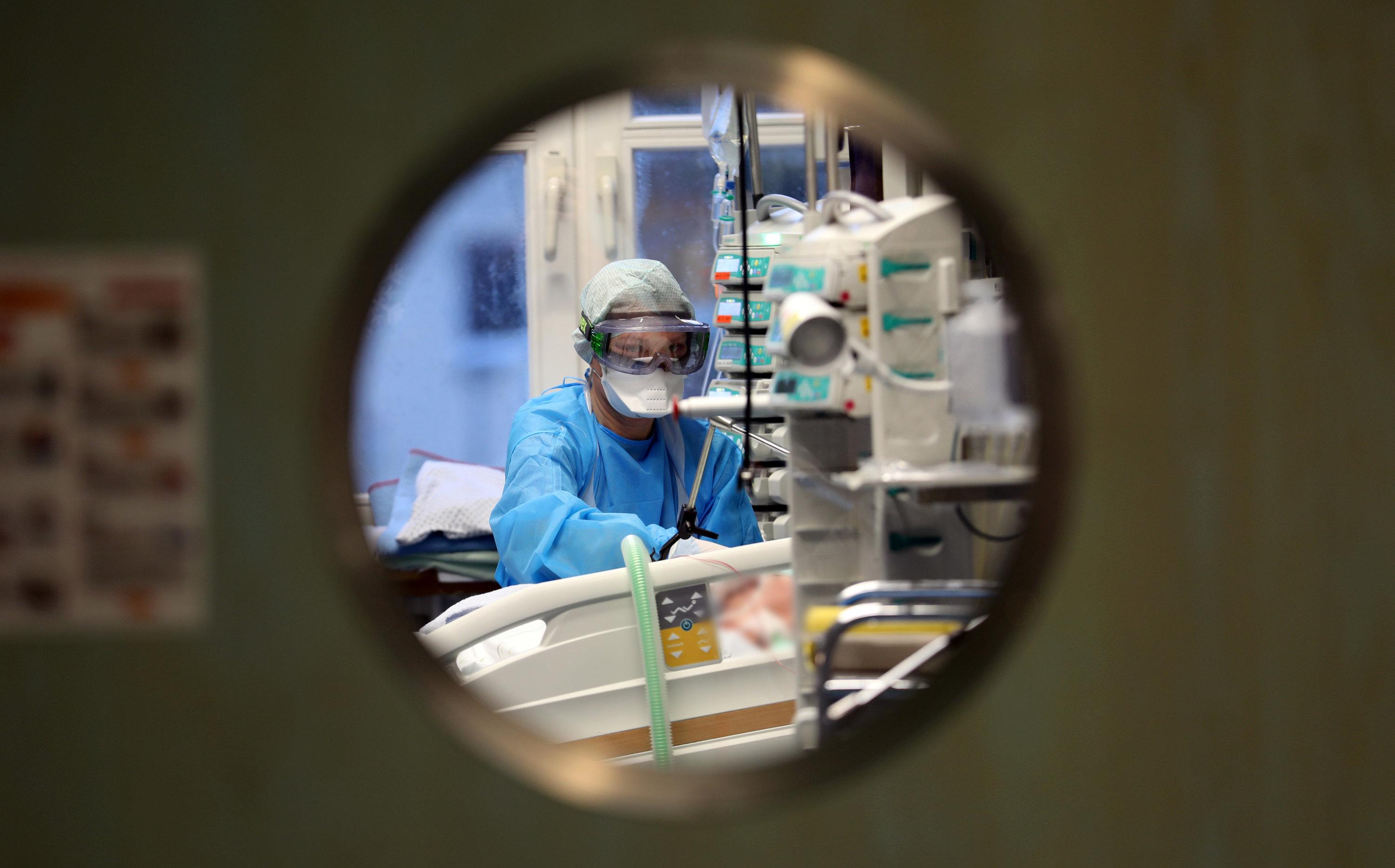 Eine Intensivpflegekraft arbeitet an einem Patienten, der im künstlichen Koma liegt. 