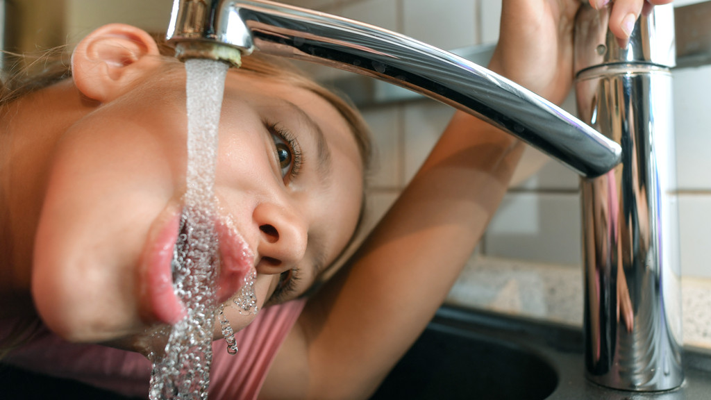Symbolbild: Ein Mädchen trinkt Leitungswasser aus einem Wasserhahn