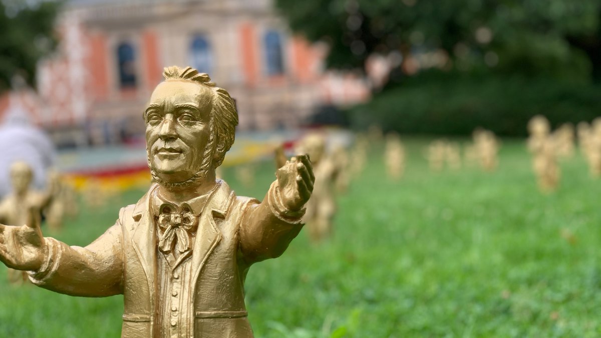Goldene Richard-Wagner-Figuren stehen vor dem Festspielhaus auf dem Grünen Hügel.