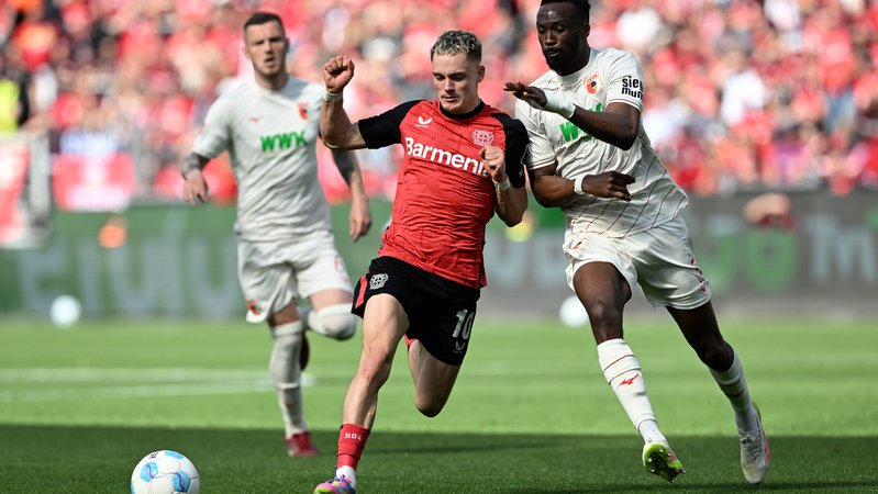 26.04.2025, Nordrhein-Westfalen, Leverkusen: Fußball: Bundesliga, Bayer Leverkusen - FC Augsburg, 31. Spieltag, BayArena, Leverkusens Florian Wirtz (l) und Augsburgs Chrislain Matsima kämpfen um den Ball. Foto: Federico Gambarini/dpa - WICHTIGER HINWEIS: Gemäß den Vorgaben der DFL Deutsche Fußball Liga bzw. des DFB Deutscher Fußball-Bund ist es untersagt, in dem Stadion und/oder vom Spiel angefertigte Fotoaufnahmen in Form von Sequenzbildern und/oder videoähnlichen Fotostrecken zu verwerten bzw. verwerten zu lassen. +++ dpa-Bildfunk +++ | Bild: dpa-Bildfunk/Federico Gambarini 26.04.2025, Nordrhein-Westfalen, Leverkusen: Fußball: Bundesliga, Bayer Leverkusen - FC Augsburg, 31. Spieltag, BayArena, Leverkusens Florian Wirtz (l) und Augsburgs Chrislain Matsima kämpfen um den Ball. Foto: Federico Gambarini/dpa - WICHTIGER HINWEIS: Gemäß den Vorgaben der DFL Deutsche Fußball Liga bzw. des DFB Deutscher Fußball-Bund ist es untersagt, in dem Stadion und/oder vom Spiel angefertigte Fotoaufnahmen in Form von Sequenzbildern und/oder videoähnlichen Fotostrecken zu verwerten bzw. verwerten zu lassen. +++ dpa-Bildfunk +++