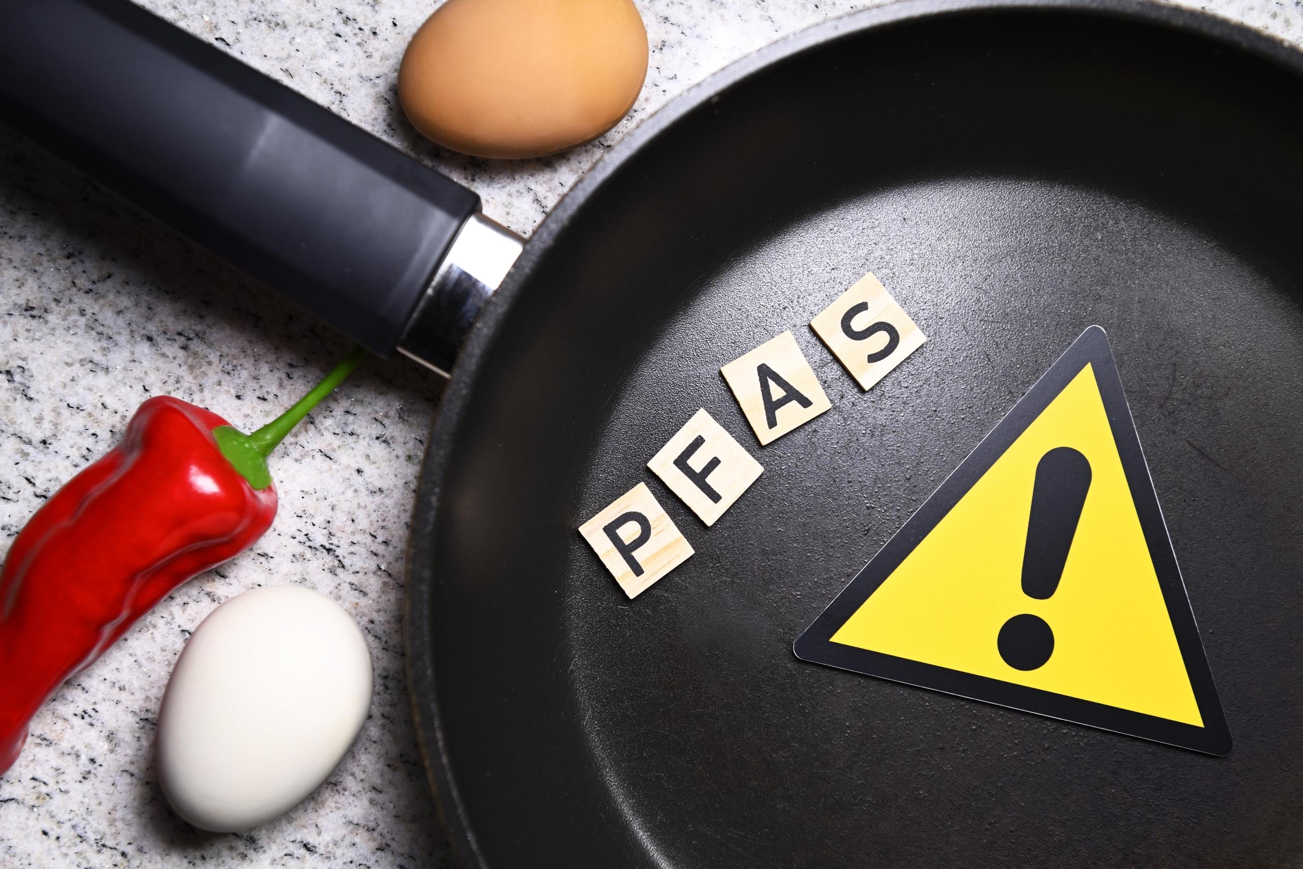Gefahrenschild mit Ausrufezeichen in Bratpfanne und Schriftzug PFAS