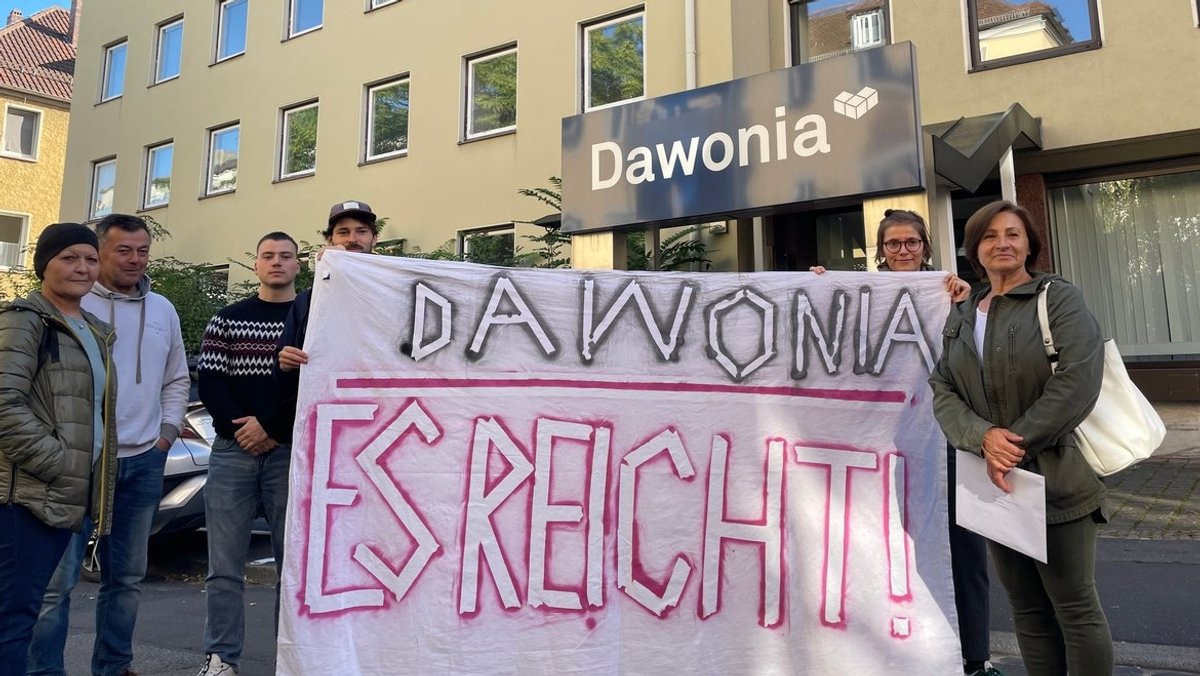 Menschen halten vor einem Gebäude in Würzburg ein Plakat mit der Aufschrift "Dawonia, es reicht!".