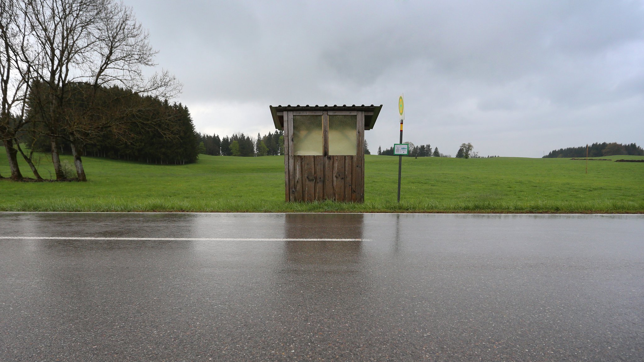 April 2019: Eine Haltestelle der Regionalverkehr Oberbayern GmbH steht an einer Landstraße im Regen.