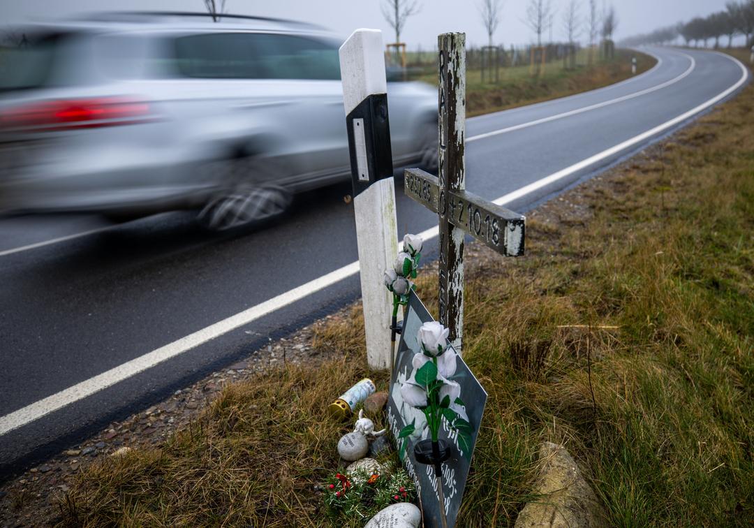 Ein Auto fährt auf einer Landstraße an einem Kreuz für ein Unfallopfer vorbei (Symbolbild).