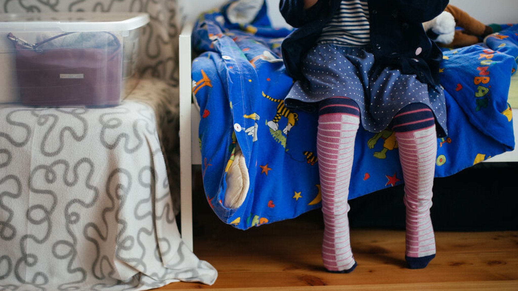 Ein Kind sitzt im Kinderzimmer auf dem Bett.