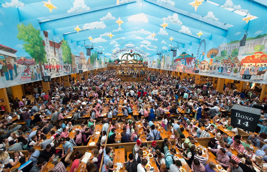 Wiesnfestzelt mit weiß-blau bemaltem Himmel und voll besetzten Biertischen, in der Mitte die Musiktribüne in Form einer Krone - Hackerzelt  | Bild:dpa Funk/ Matthias Balk