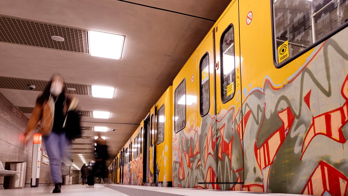 Eine Frau geht an einem Bahnsteig an einer Berliner U-Bahn entlang.